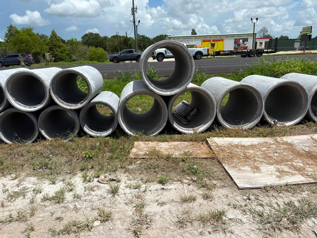 Stacked Texas Precast reinforced concrete culvert pipe in several diameters in the yard