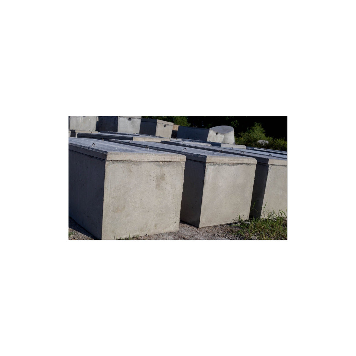 Row of Texas Precast rectangular concrete interceptor tanks in the manufacturing yard