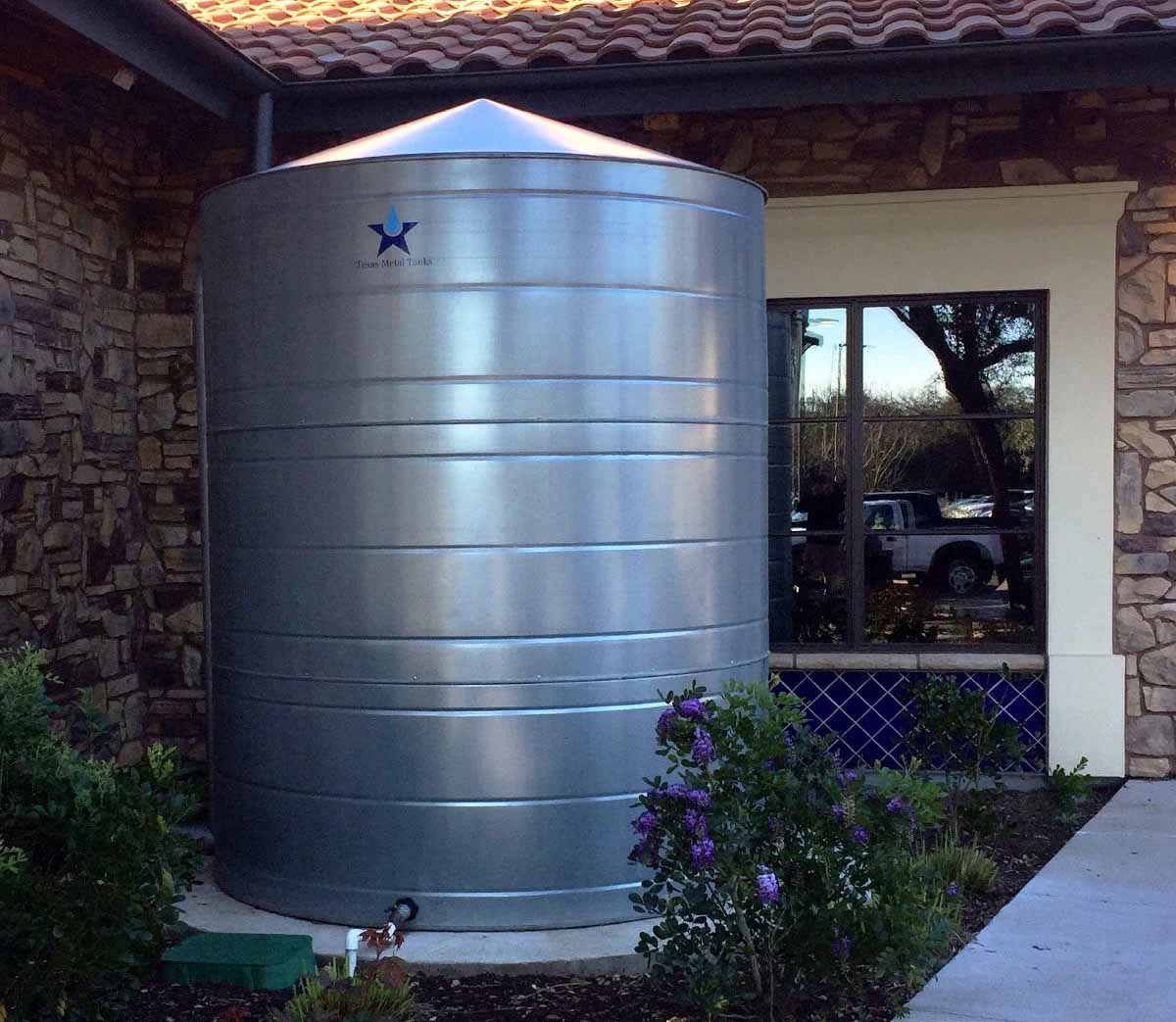 Texas Metal Tanks galvanized steel rainwater tank installed beside a stone building